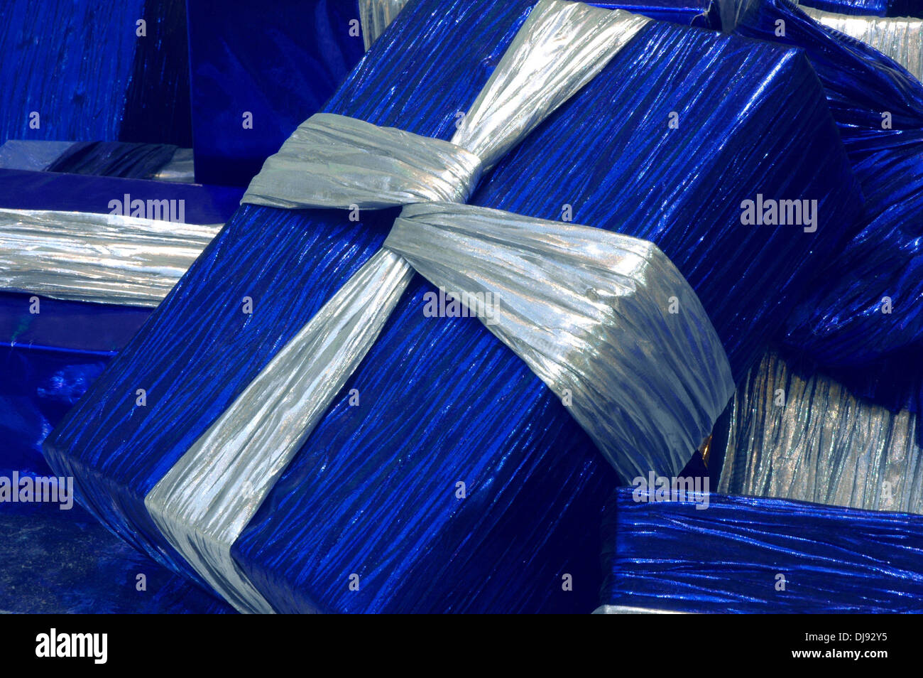 Christmas packages wrapped in blue paper with silver ribbons are ...