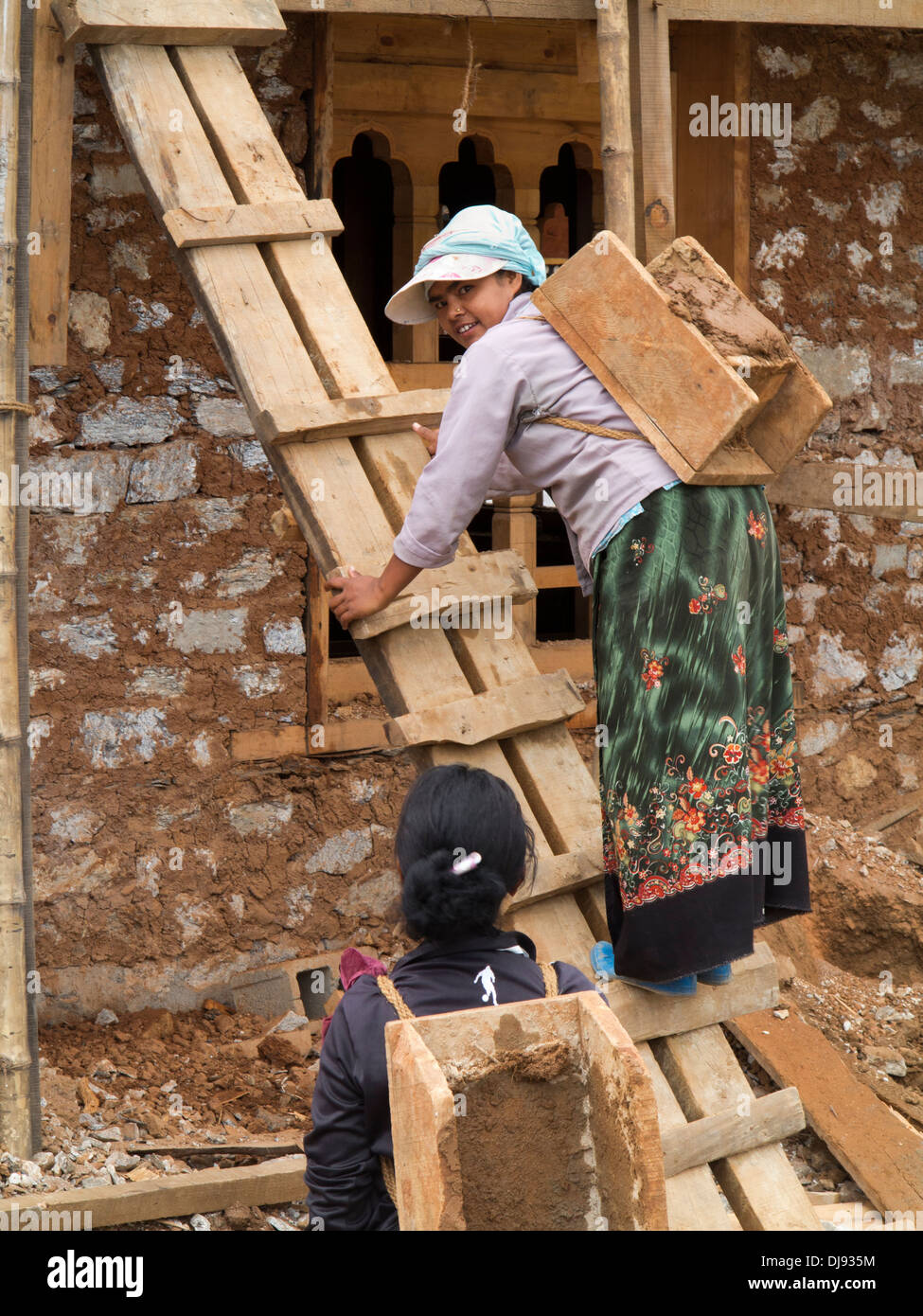 Bhutan, Wangdue Phodrang, house construction, woman labourer climbing ladder with load Stock Photo