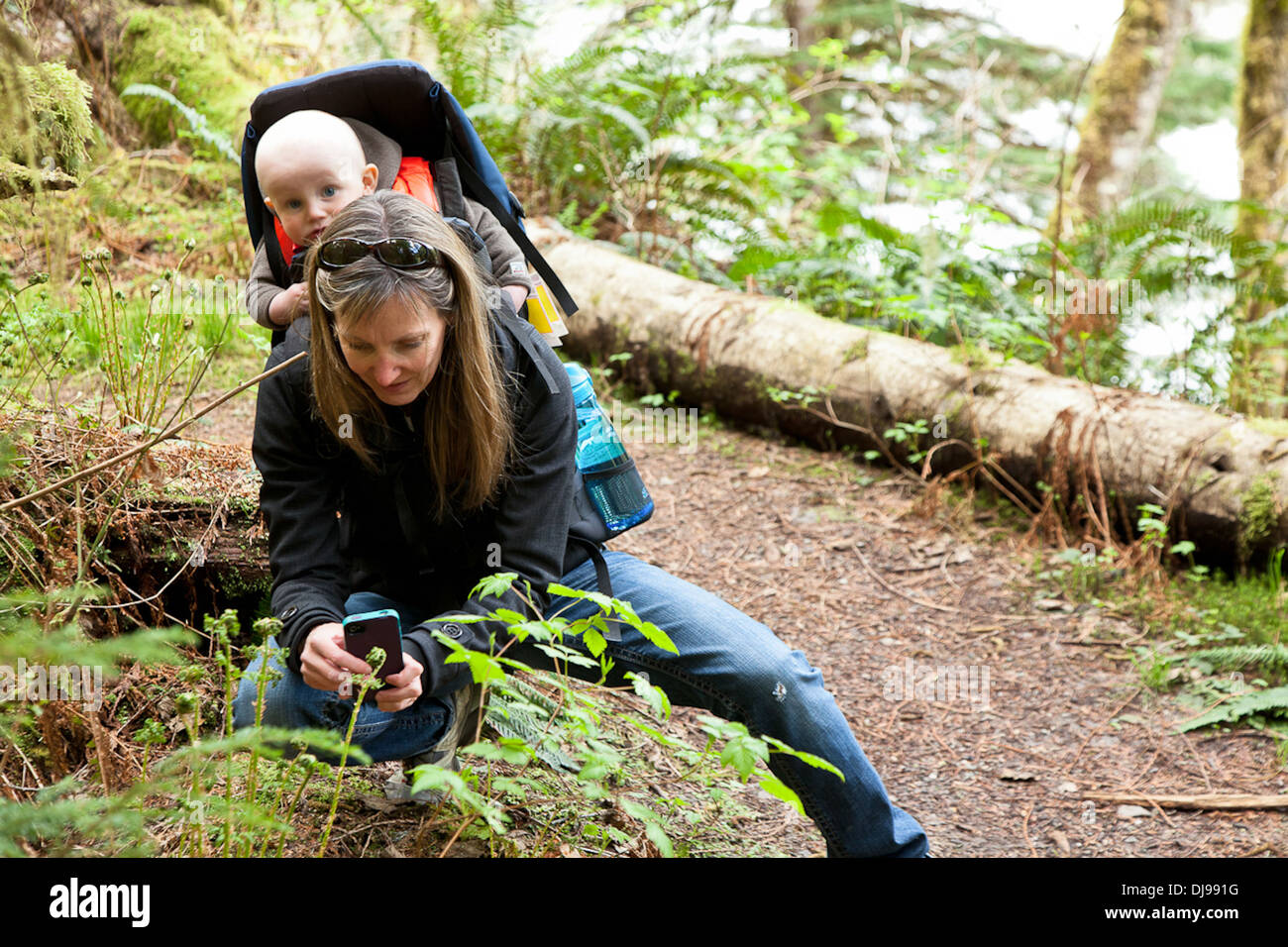 Caucasian mother carrying baby in forest - Smartphone Captured Stock Image