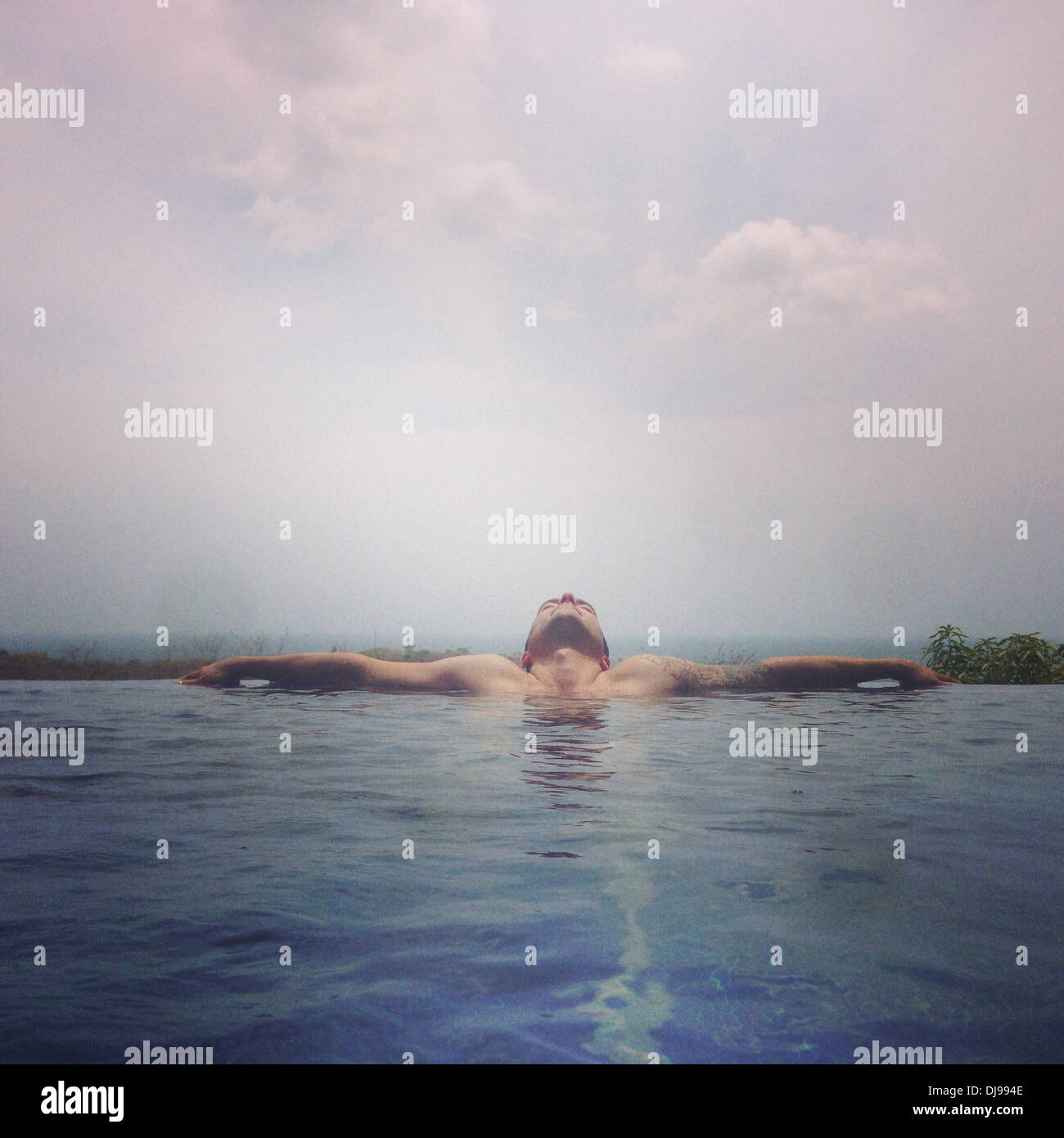 Man relaxing in infinity pool - Smartphone Captured Stock Image