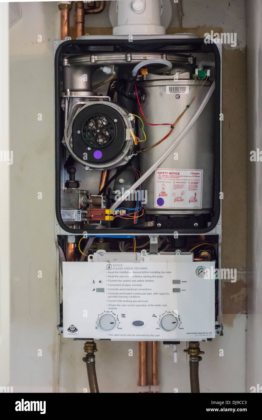Condensing combi gas boiler without the front cover.  Two pipes are connected to power flush the system. Stock Photo