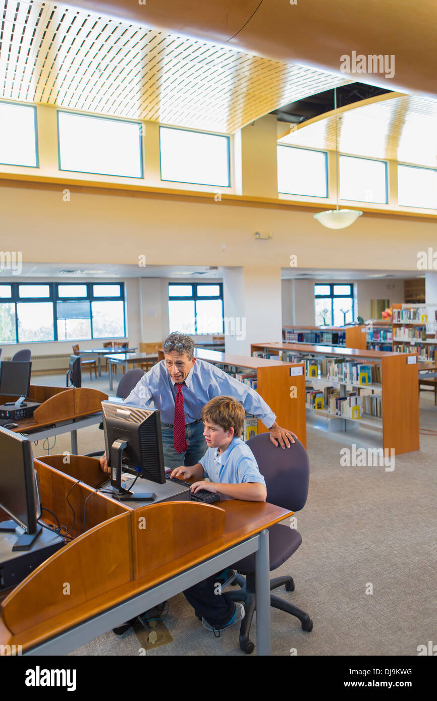 Teacher and student working at computer in library Stock Photo