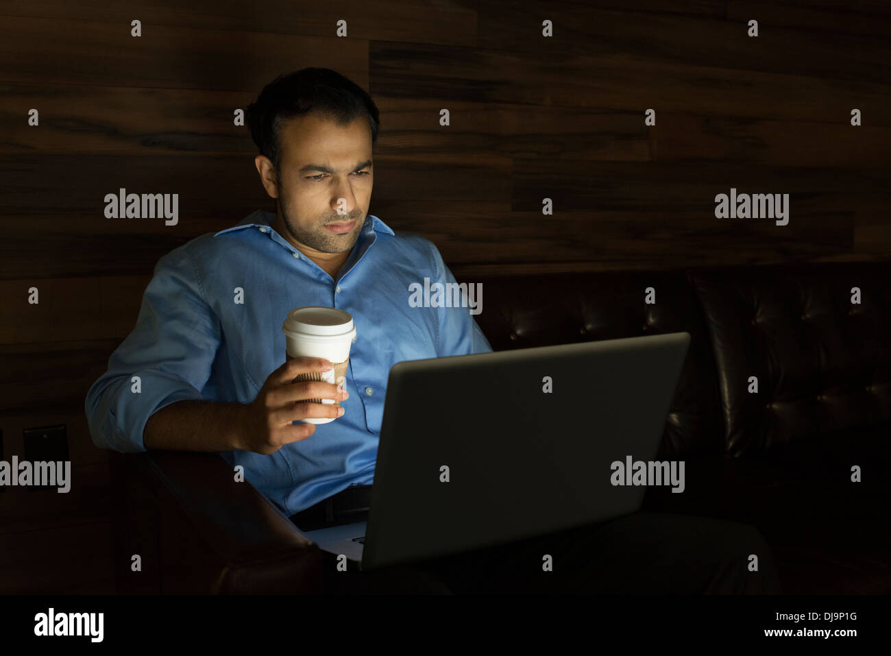 Businessman using laptop on sofa at night Stock Photo