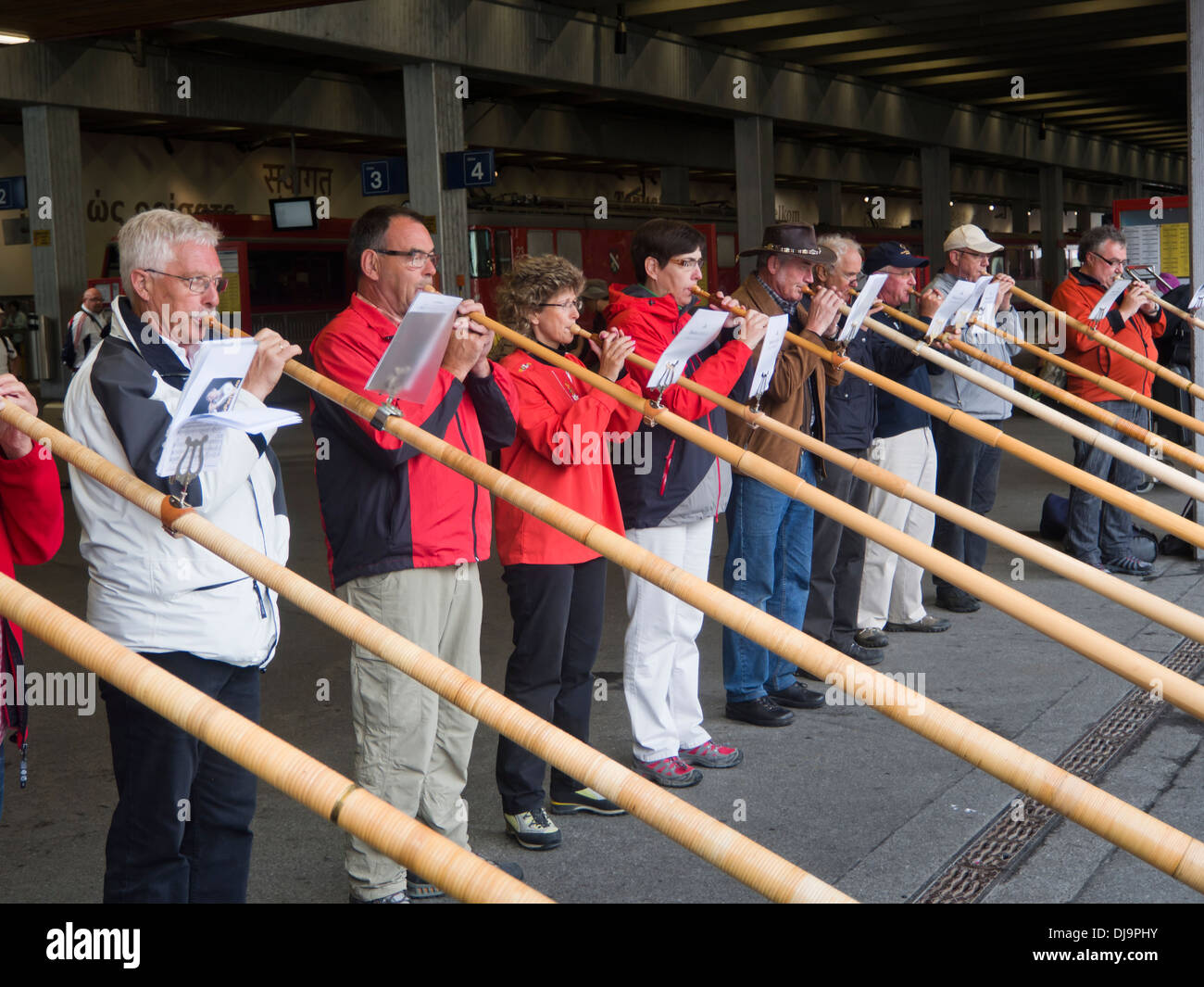 Row of musicians performing on  the alphorn for tourists in the Zermatt railway station , Switzerland Stock Photo