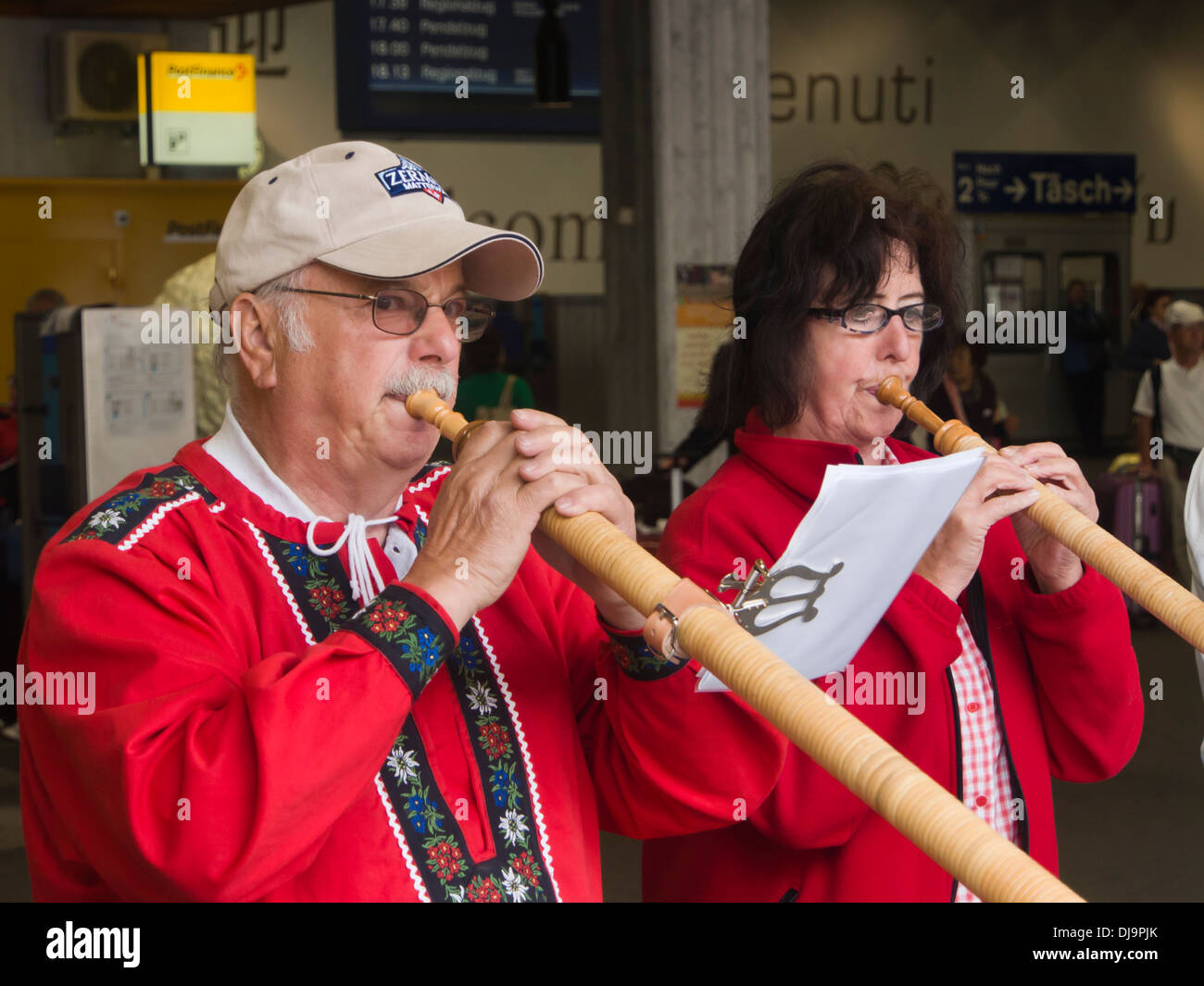 Close up of two musicians performing on  the alphorn for tourists in the Zermatt railway station, Switzerland Stock Photo