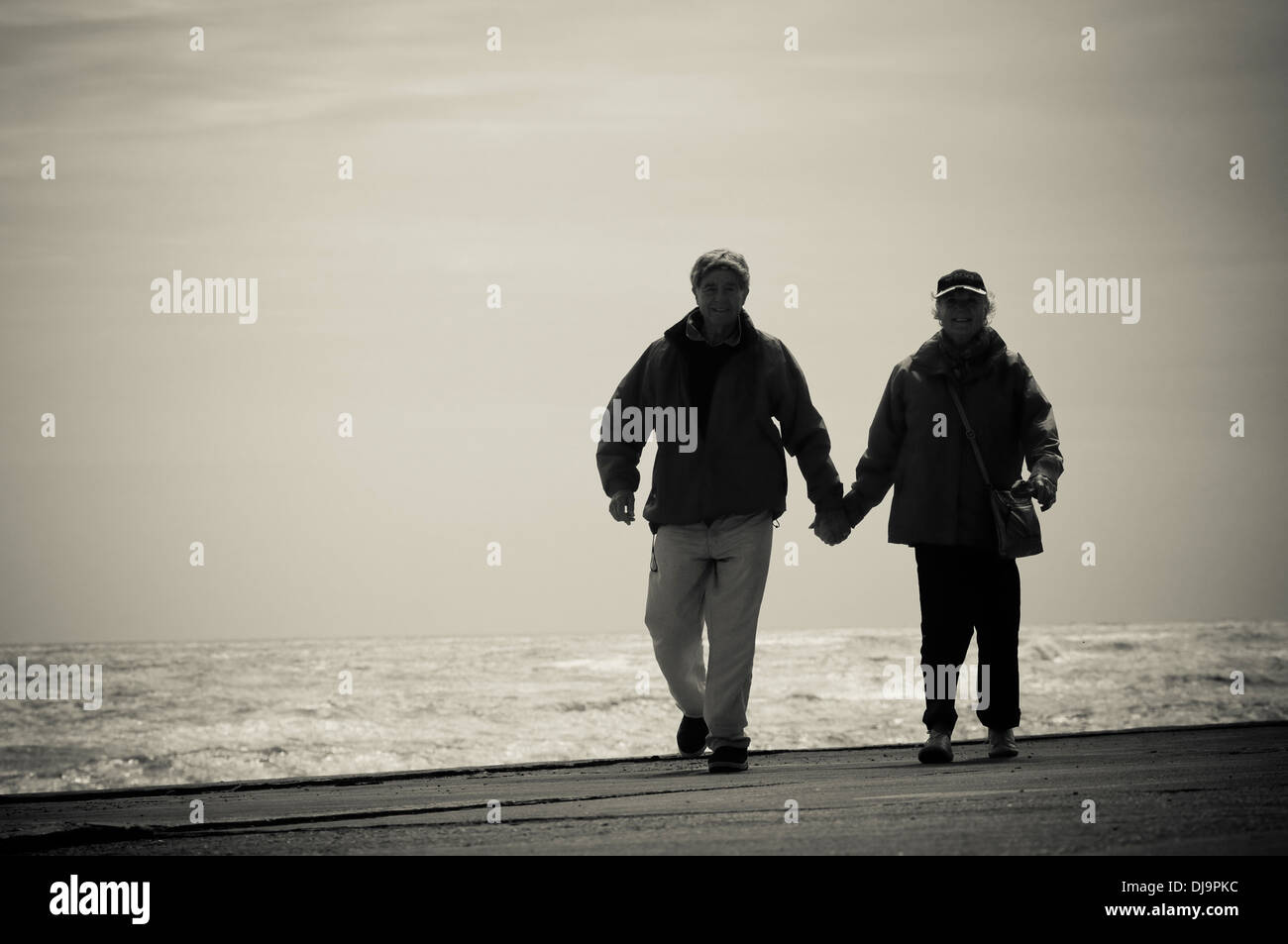 Elderly couple walking hand in hand on a beach Stock Photo - Alamy
