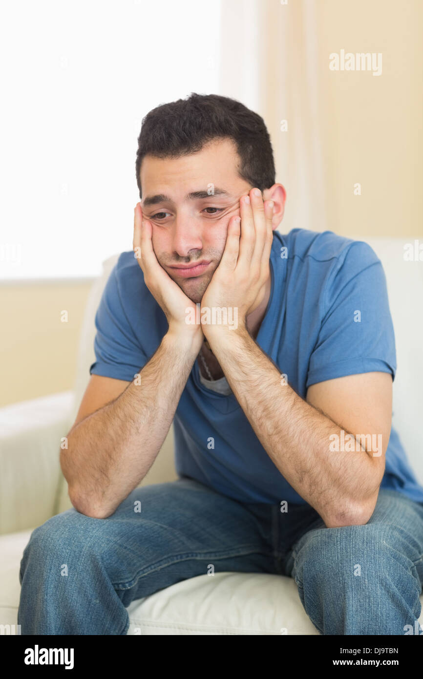 Casual sad man sitting on couch Stock Photo