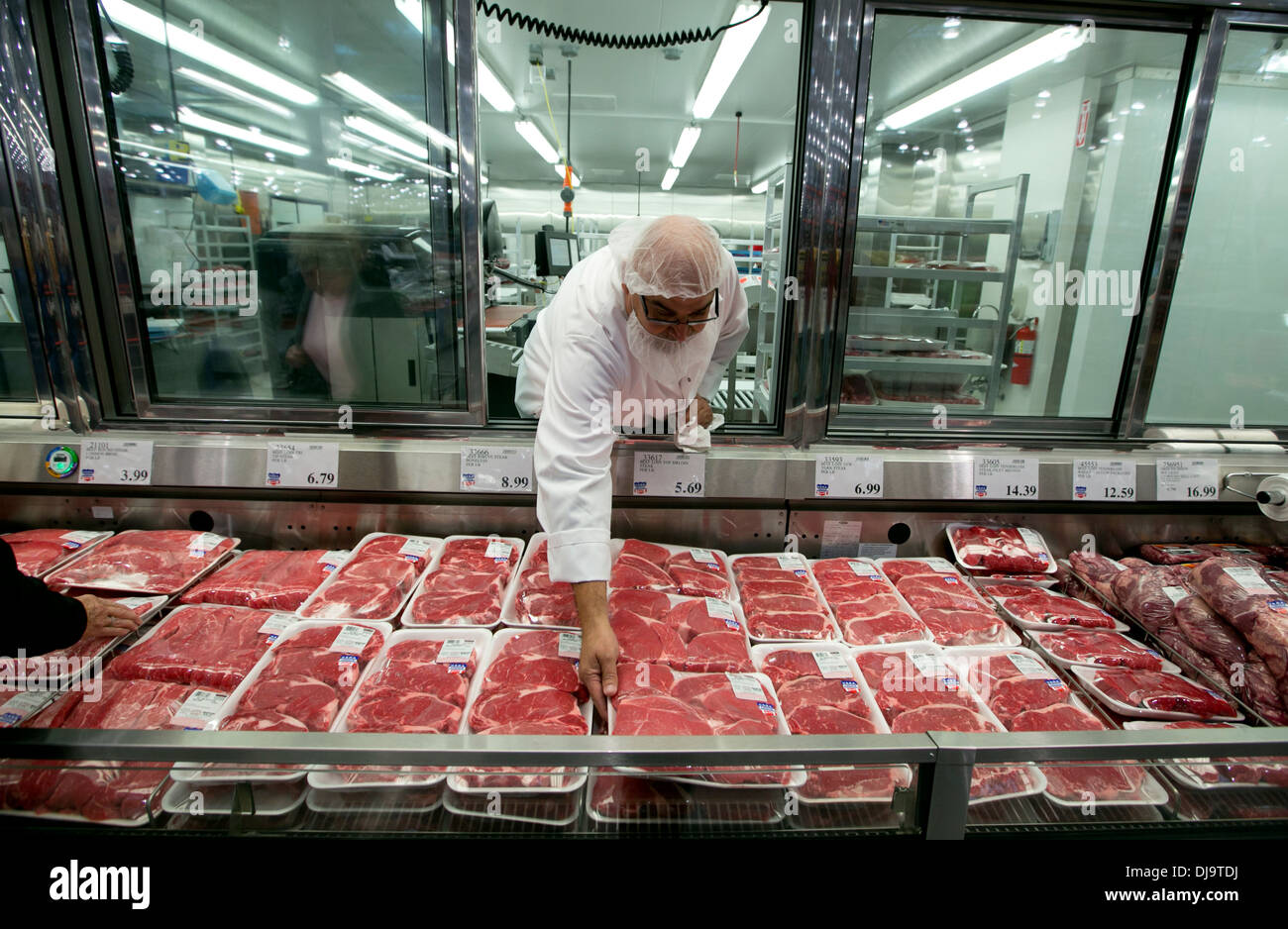 Hispanic employee wearing food safety hair net stocks with fresh meat department at a newly open COSTCO warehouse retail store Stock Photo