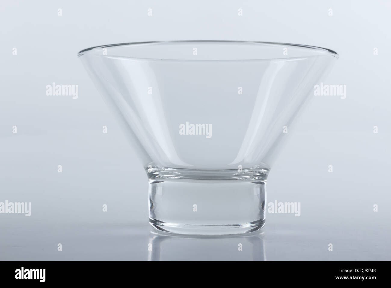 an empty glass ice cream bowl on a light gray reflecting surface Stock Photo