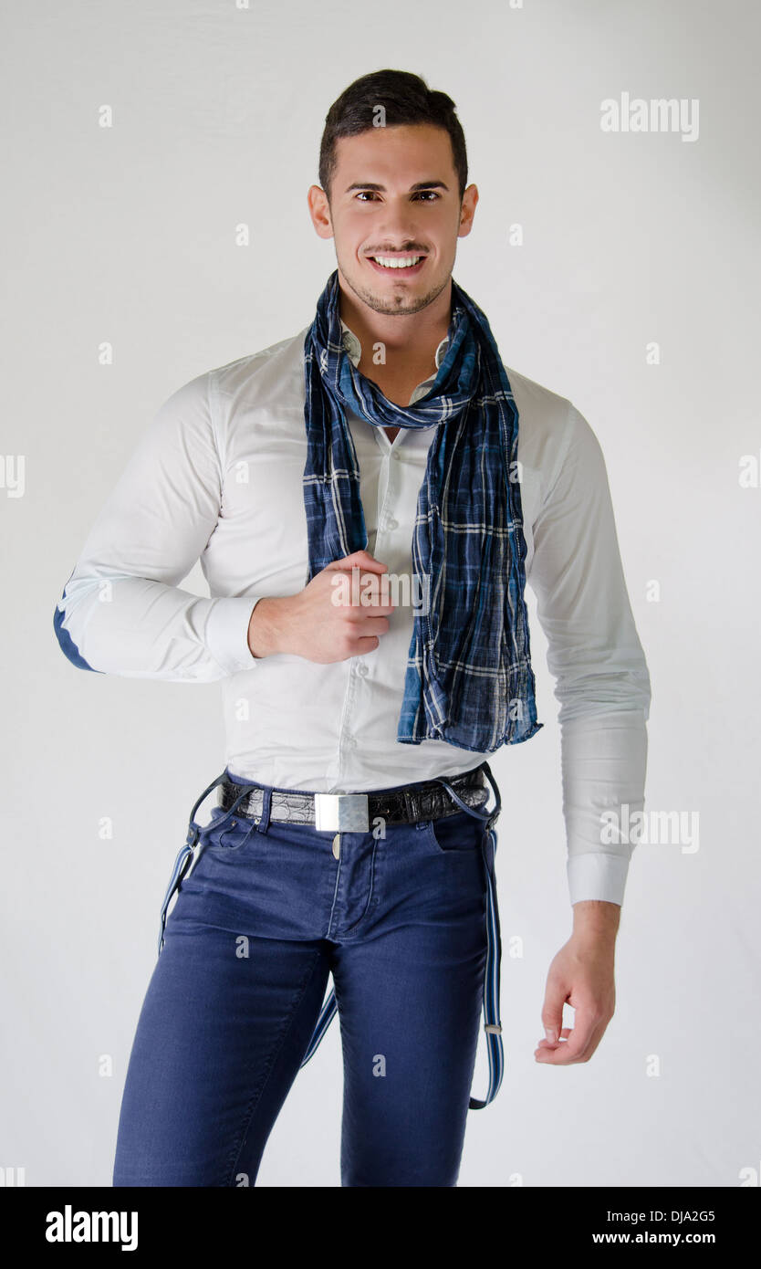 Elegant young man with white shirt and blue scarf, smiling on light background Stock Photo