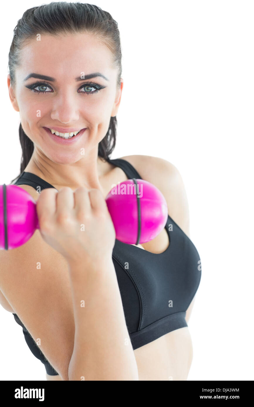 Joyful attractive woman smiling at camera while training with a dumb-bell Stock Photo