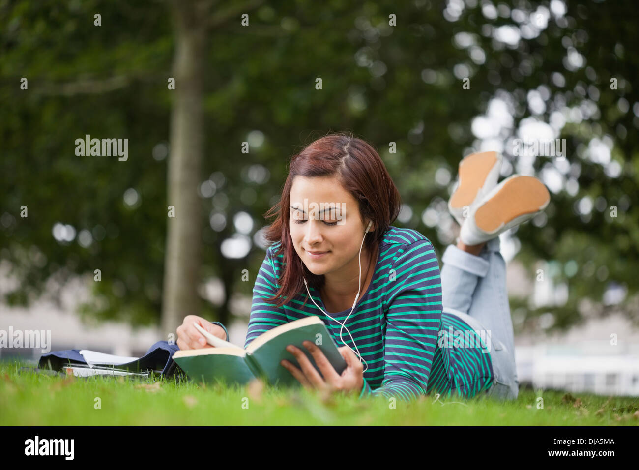 Calm casual student lying on grass reading Stock Photo