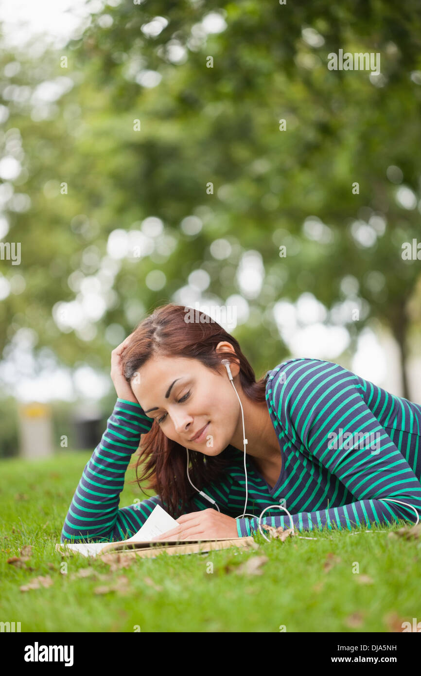Casual student lying on grass reading Stock Photo