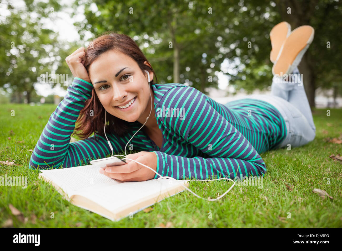 Happy casual student lying on grass listening to music Stock Photo - Alamy