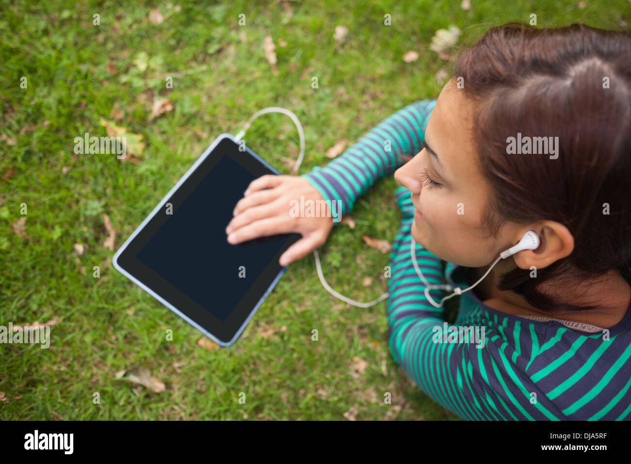 Casual student lying on grass using tablet Stock Photo