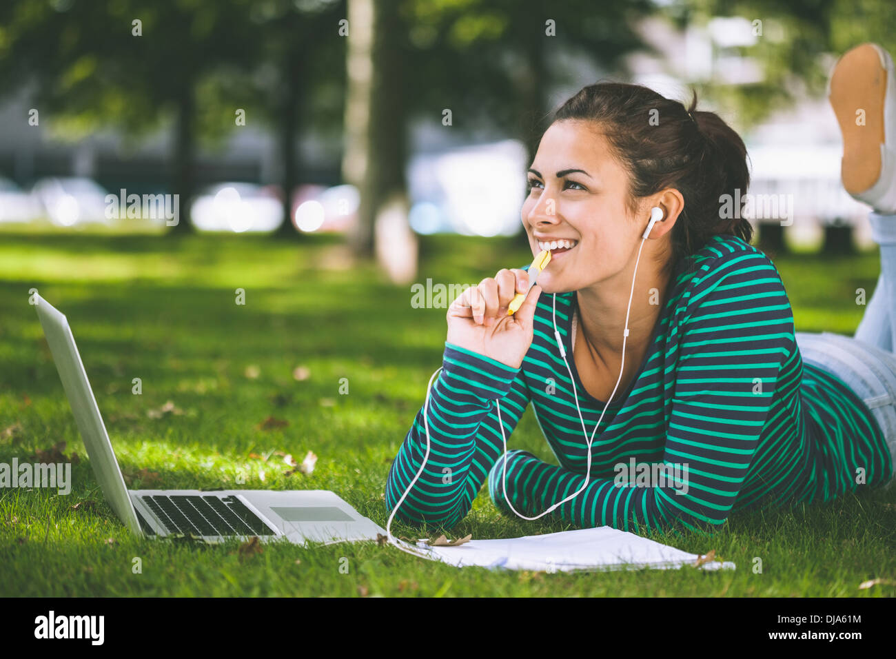 Laughing casual student lying on grass taking notes Stock Photo