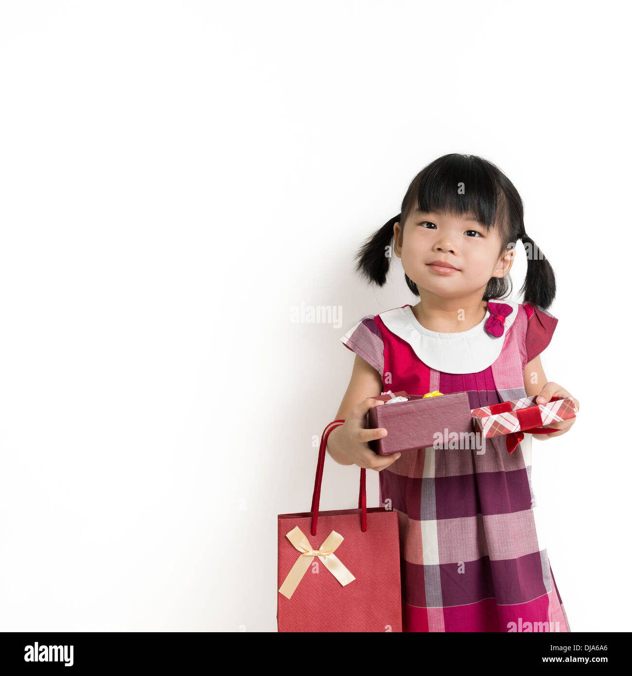 Portrait of little girl holding gift box and bag Stock Photo - Alamy
