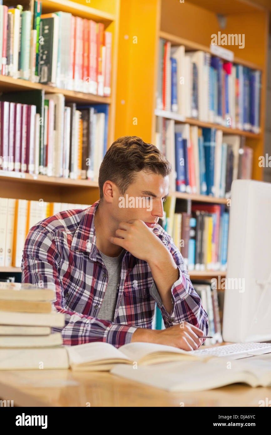 Handsome thoughtful student using computer Stock Photo