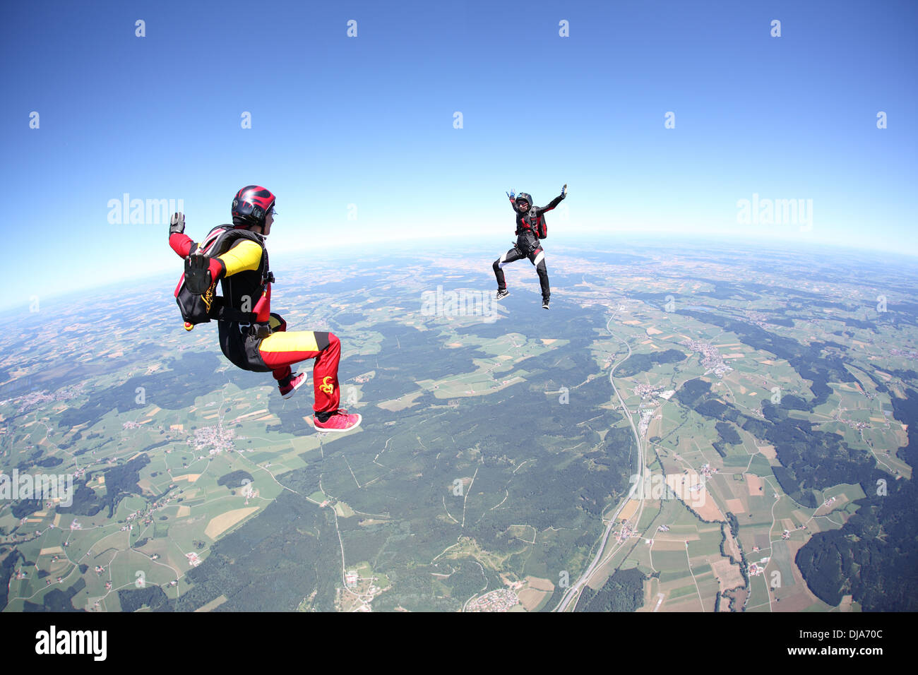 Skydivers are jumping out of an airplane and playing together. It is fun for all to fly free over nice landscape. Stock Photo