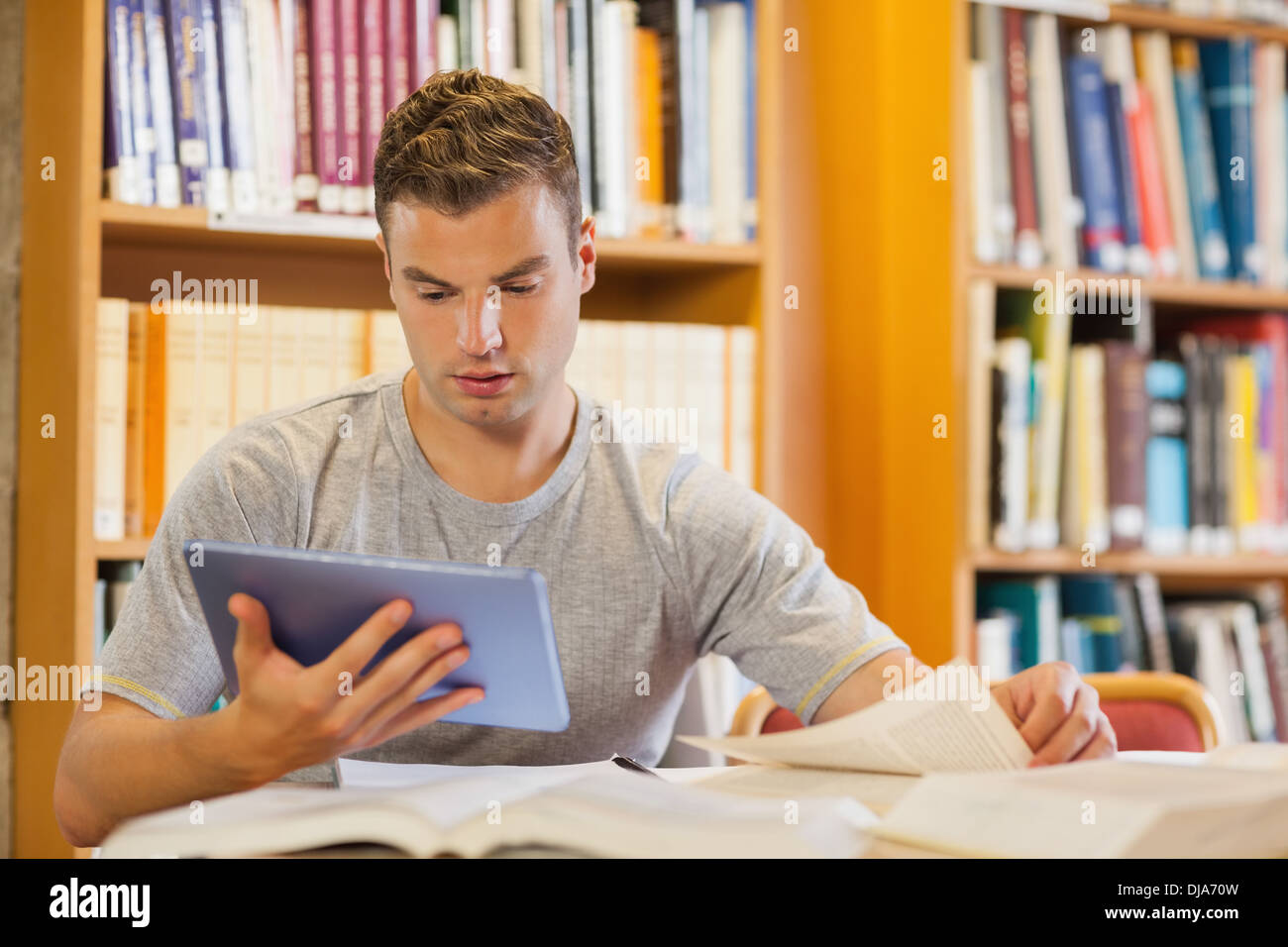 Attractive focused student using tablet and turning page Stock Photo