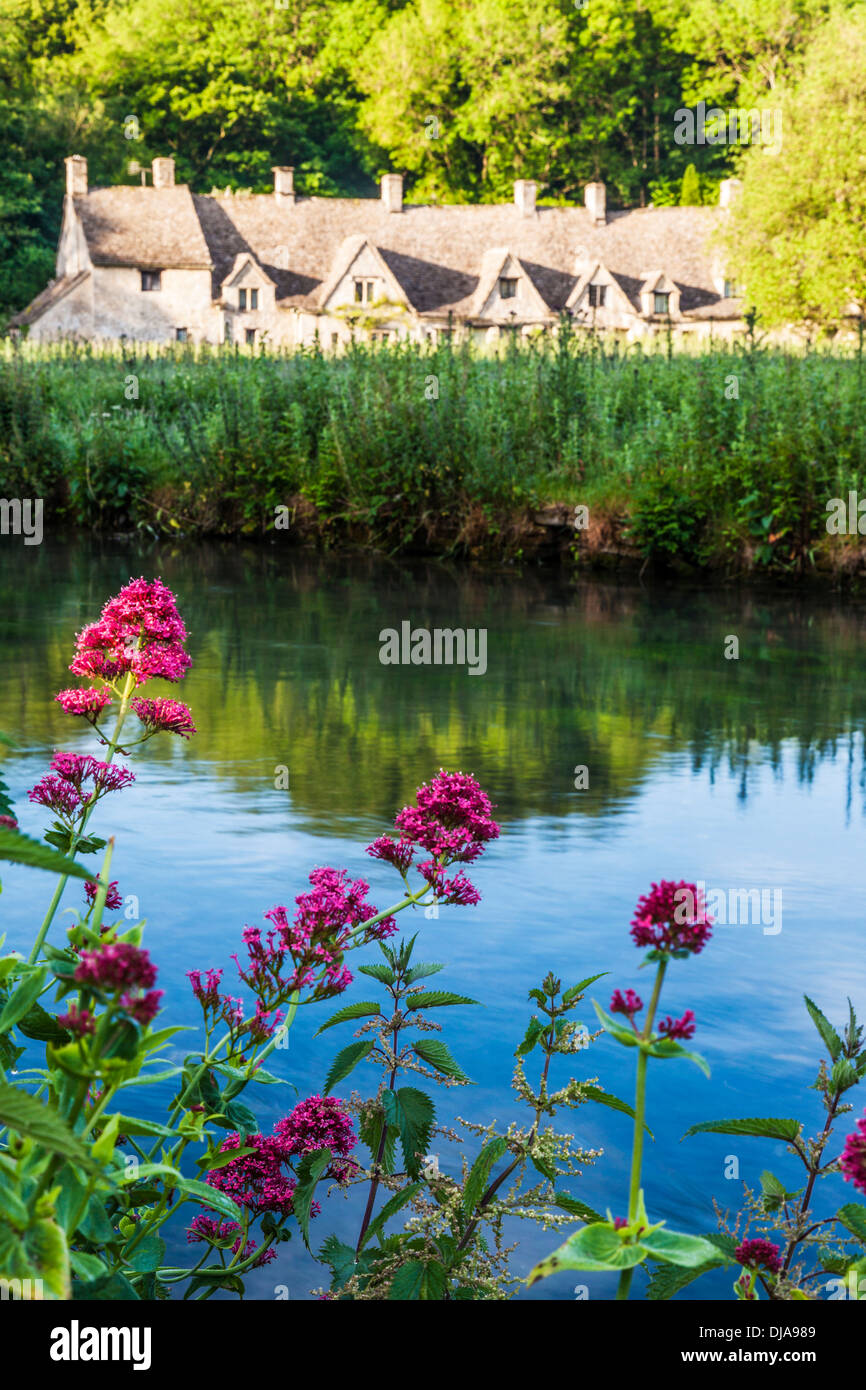 View over the River Coln and the Rack Isle water meadow to the famous Arlington Row cottages in the Cotswold village of Bibury. Stock Photo