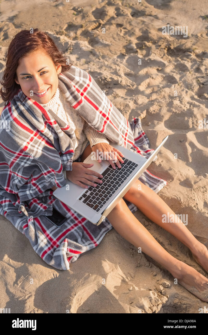 Woman covered with blanket using laptop at beach Stock Photo Alamy