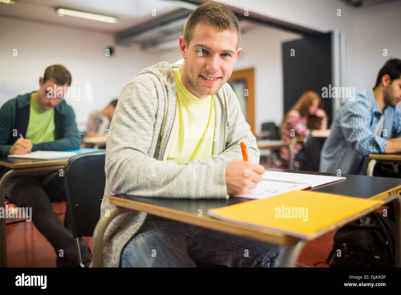 Smiling student with others writing notes in classroom Stock Photo