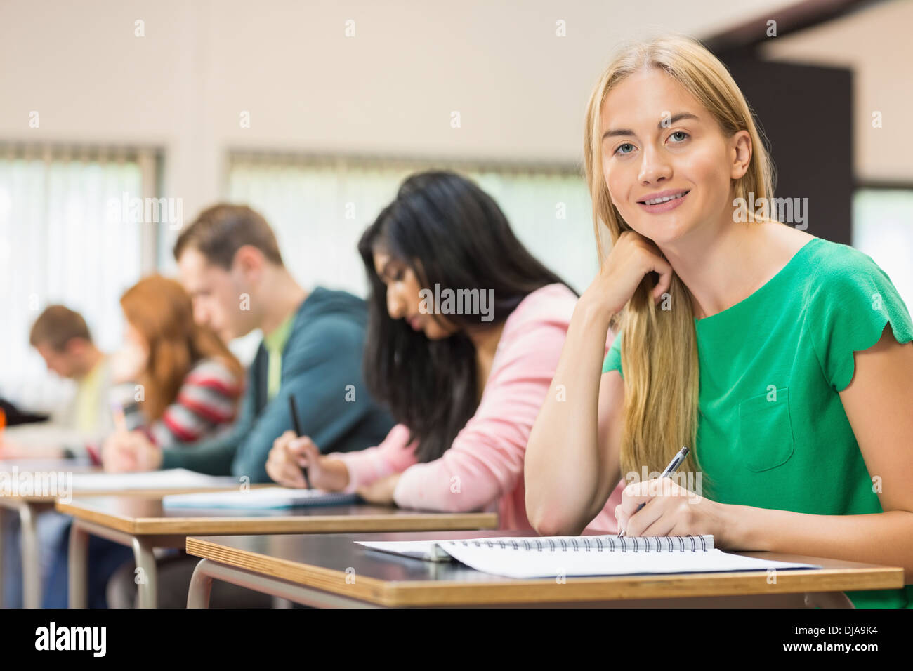 Female student with others writing notes in classroom Stock Photo