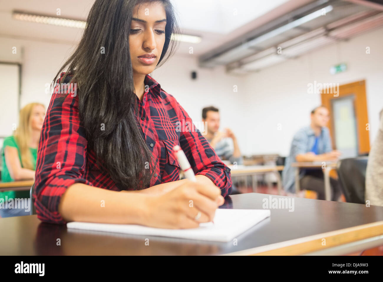 Female student with others writing notes in classroom Stock Photo