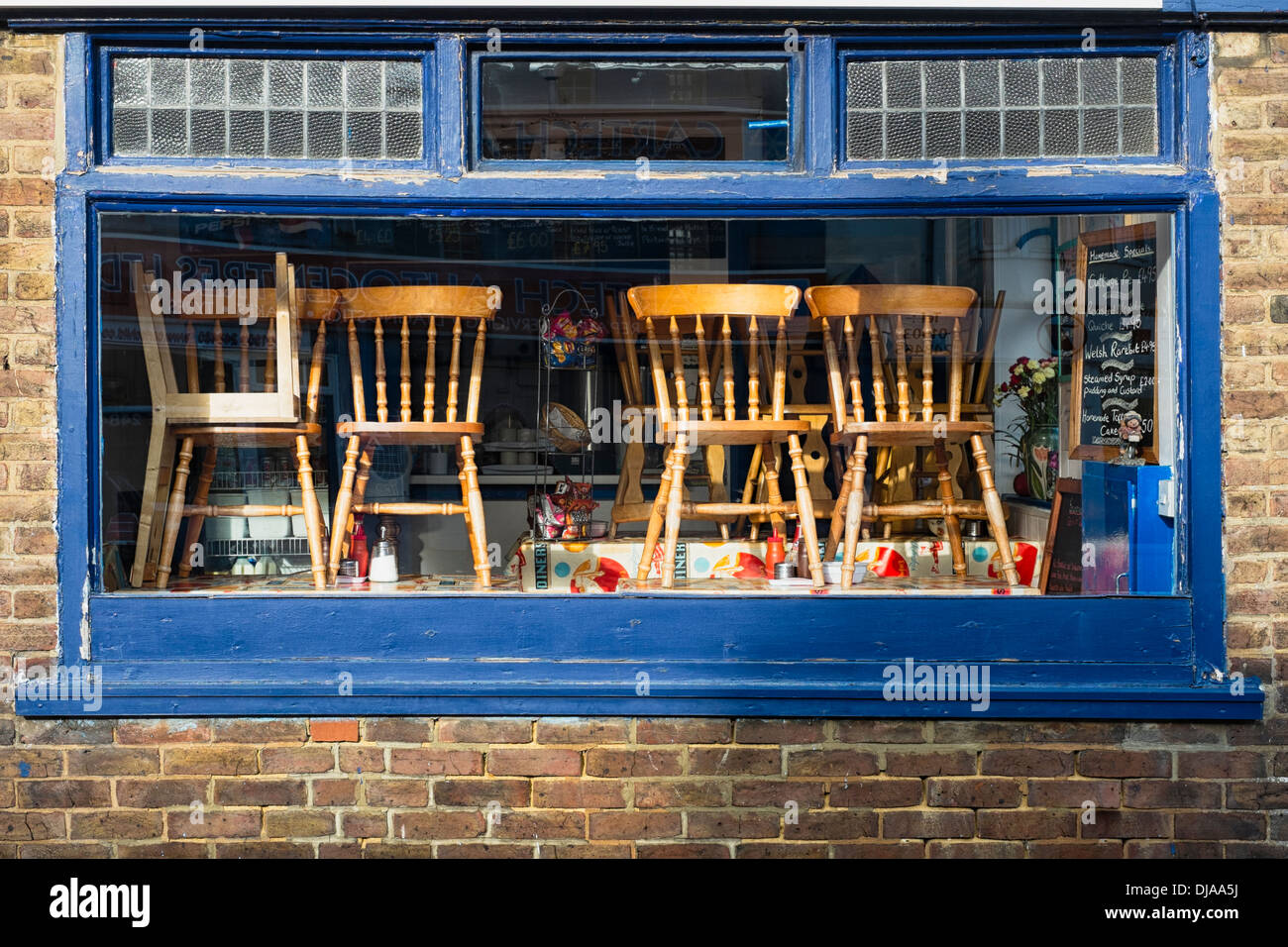 Chairs stacked on tables in a closed cafe window Stock Photo