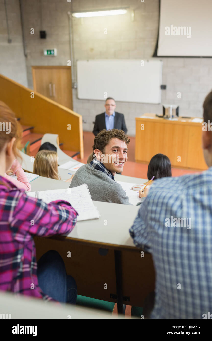 Smiling male with students and teacher at lecture hall Stock Photo