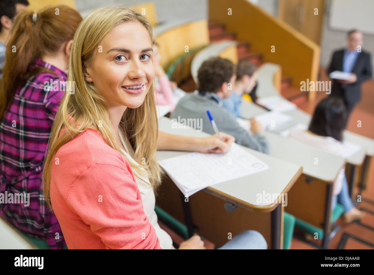 Smiling female with students and teacher at lecture hall Stock Photo