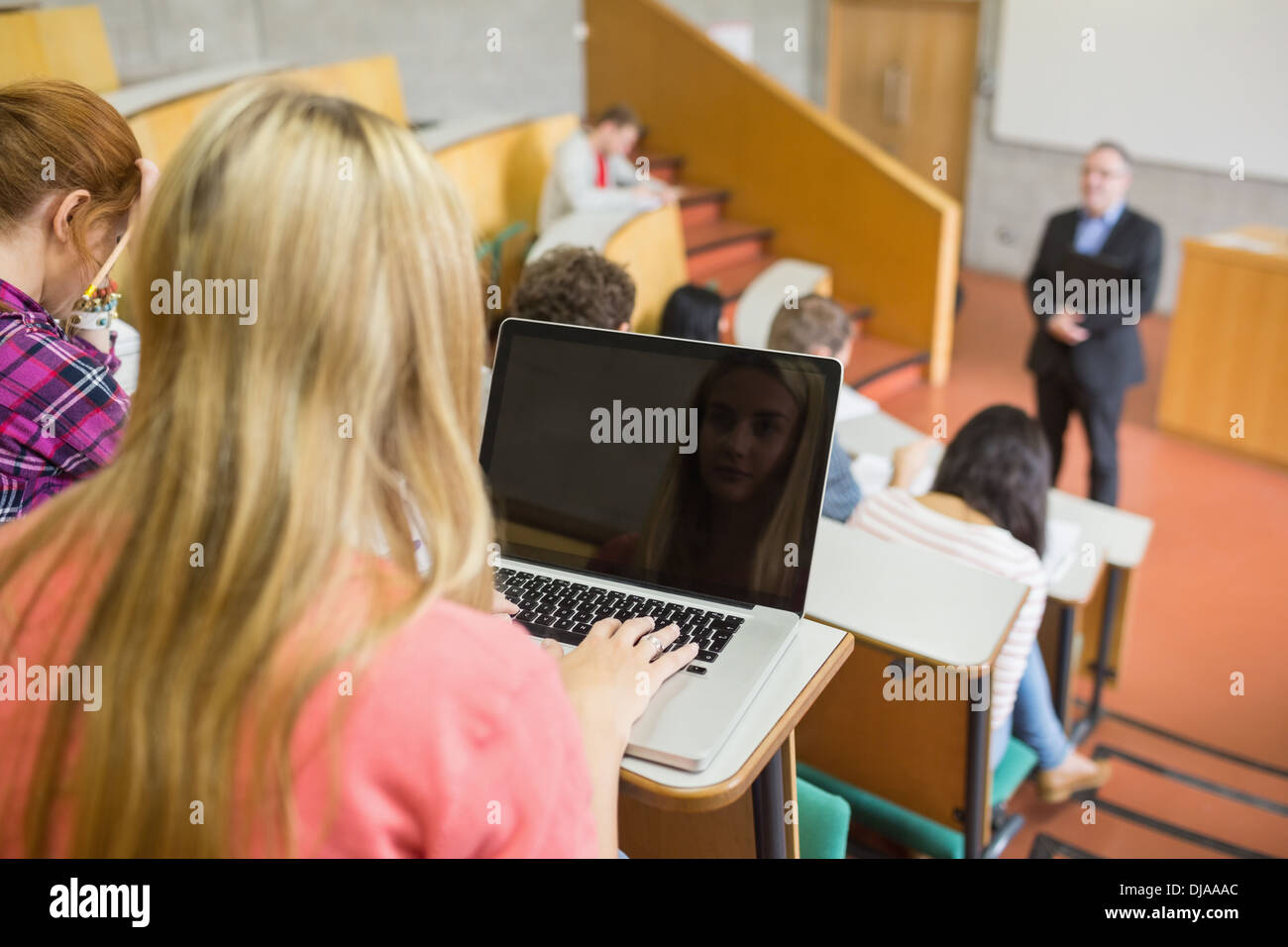 Female using laptop with students and teacher at lecture hall Stock Photo