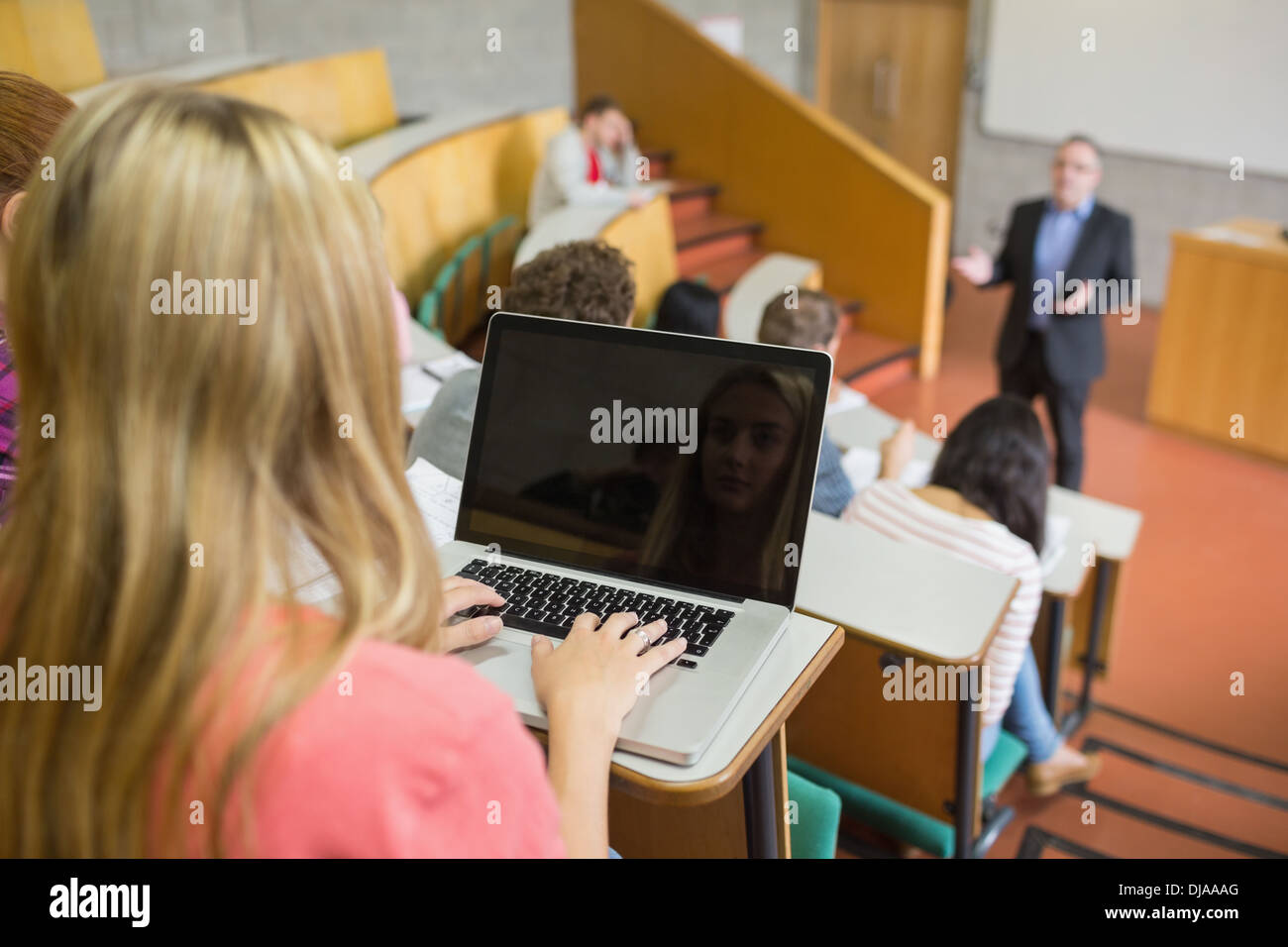 Female using laptop with students and teacher at lecture hall Stock Photo