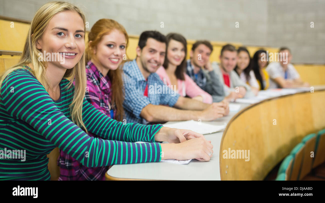 Smiling students sitting in a row at the lecture hall Stock Photo