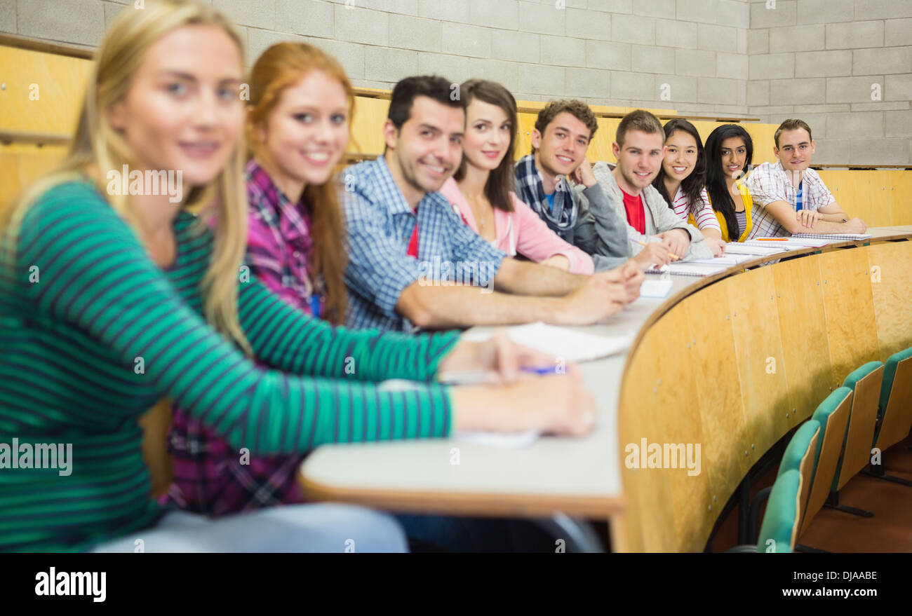 Smiling students sitting in a row at lecture hall Stock Photo