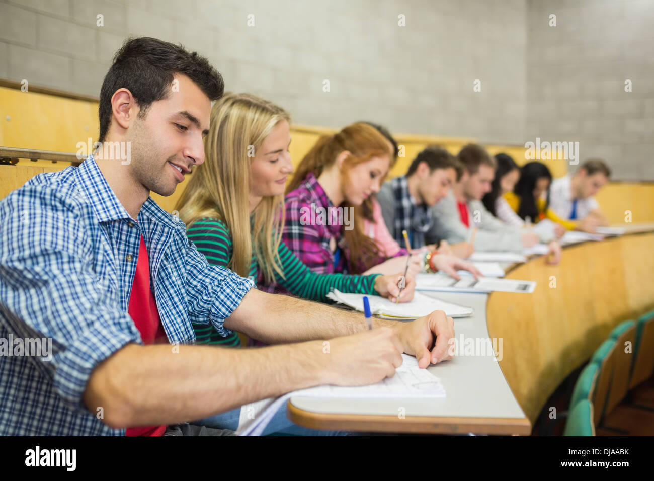 Students writing notes in a row at lecture hall Stock Photo