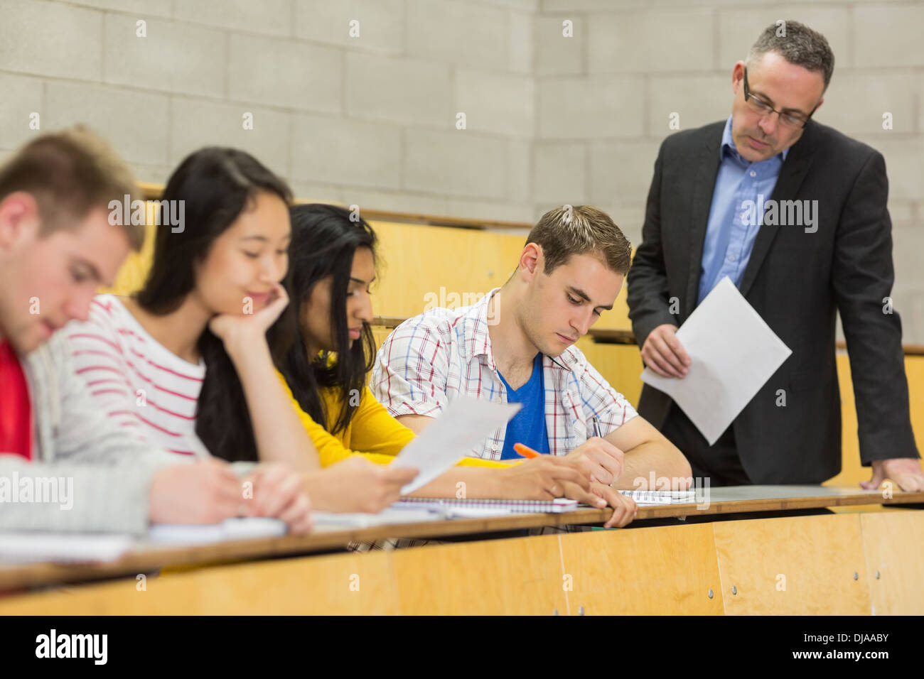Teacher with students writing notes in lecture hall Stock Photo