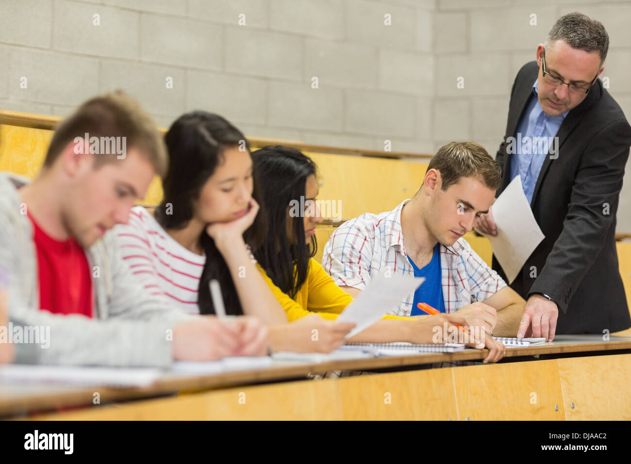 Teacher with students writing notes in lecture hall Stock Photo