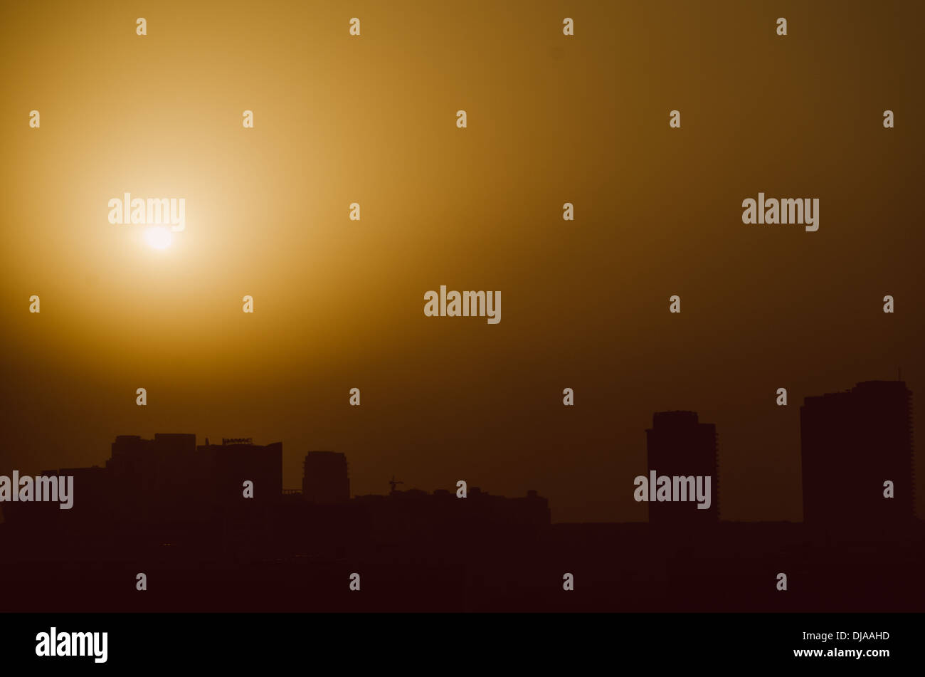 The sun sets behind a thick layer of sand in the horizon at Dubai Media City. Dubai, United Arab Emirates. Stock Photo