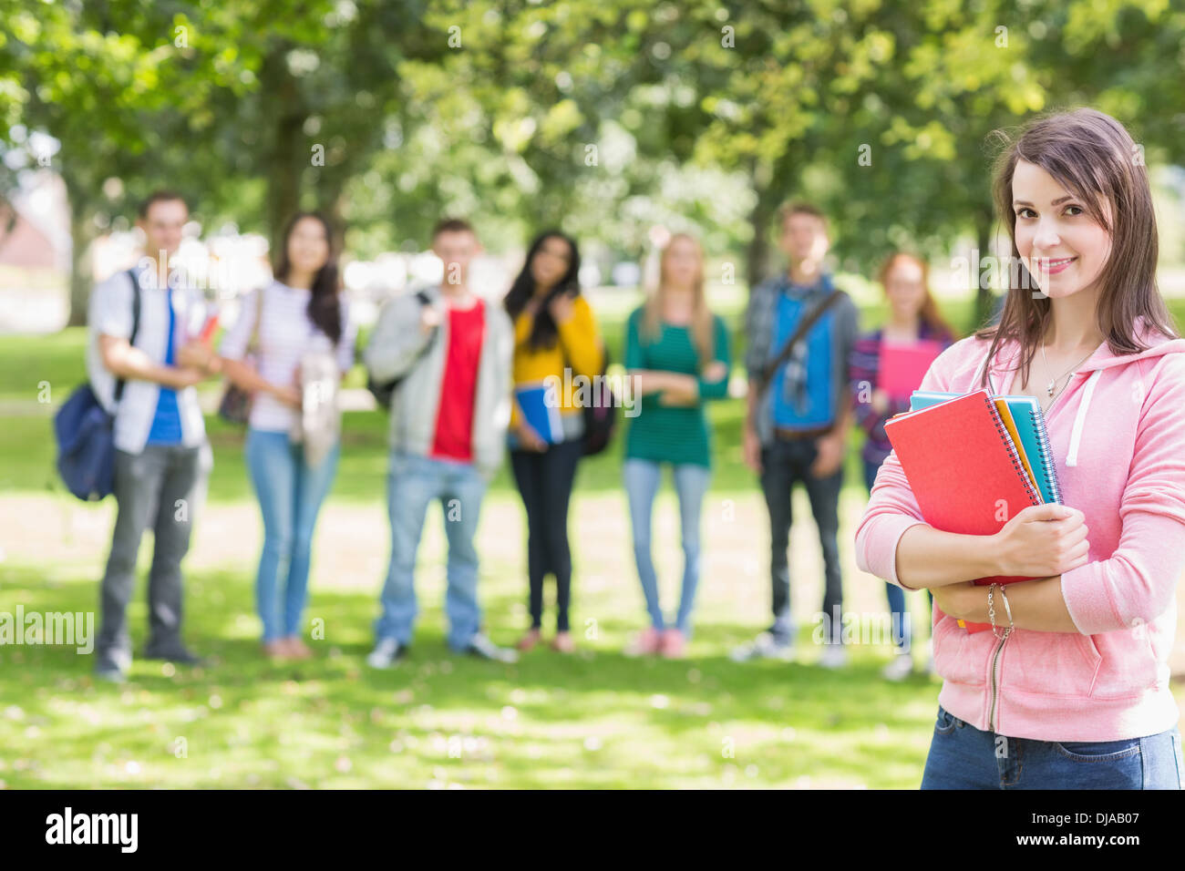 College girl holding books with students in park Stock Photo - Alamy