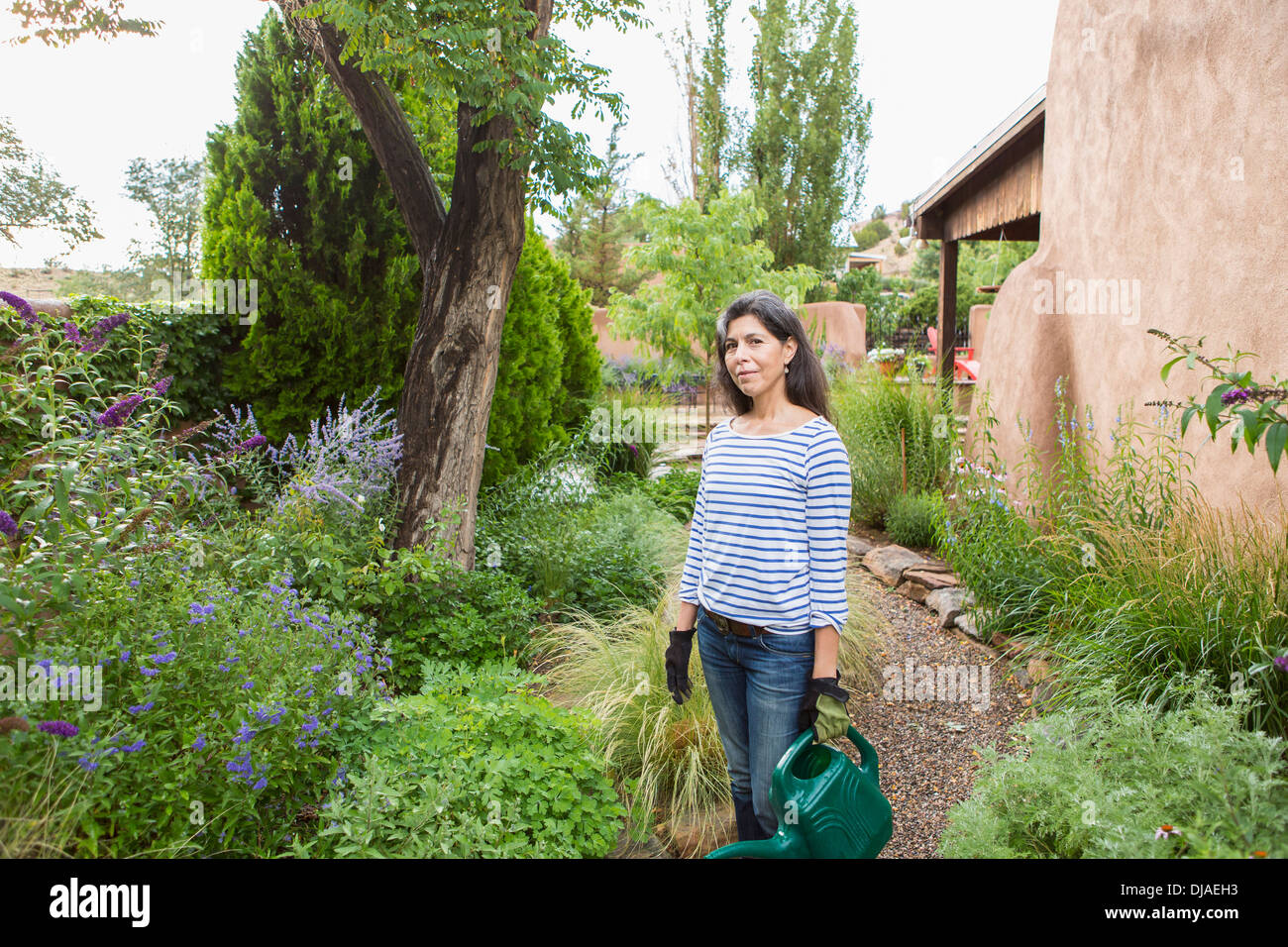 Hispanic woman watering flowers in garden Stock Photo