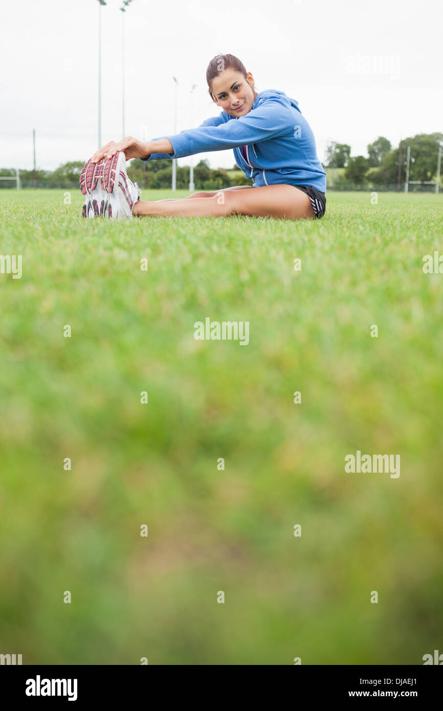 Sporty woman stretching her legs while sitting on grass Stock Photo - Alamy