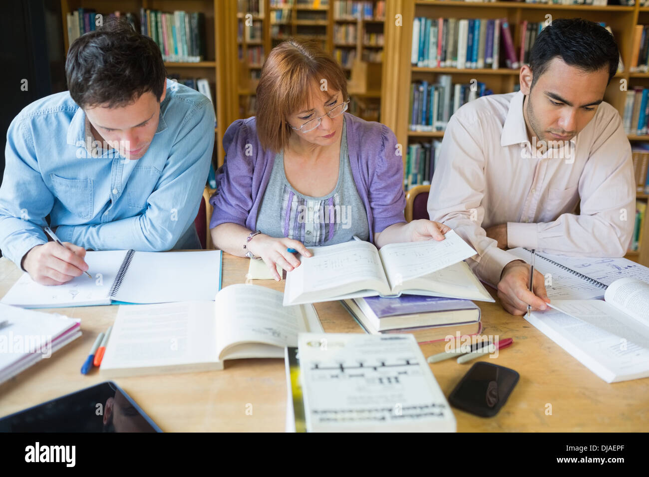 Adult students studying together in the library Stock Photo