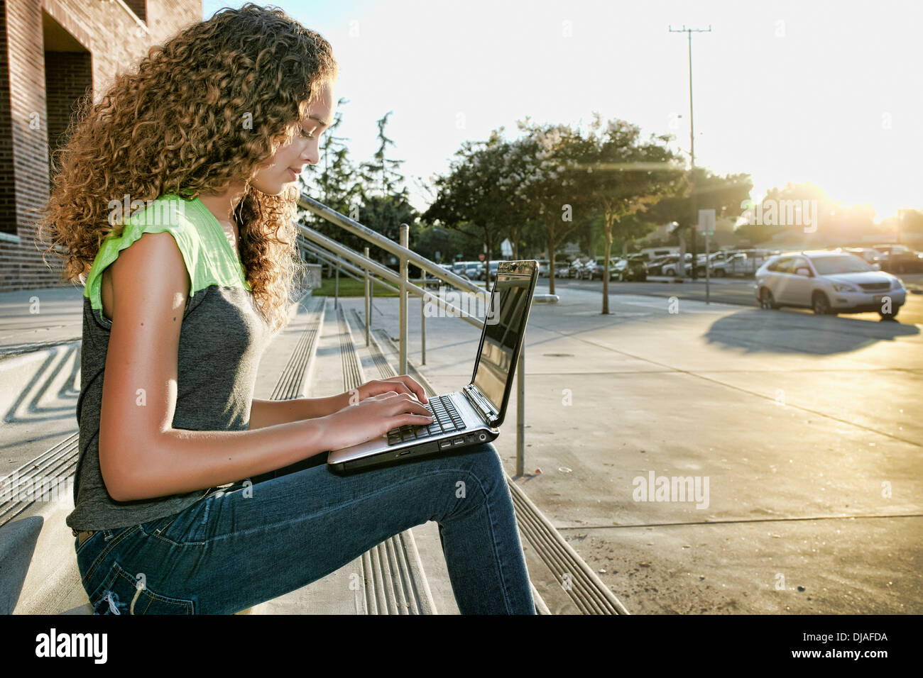 Mixed race girl using laptop on steps Stock Photo