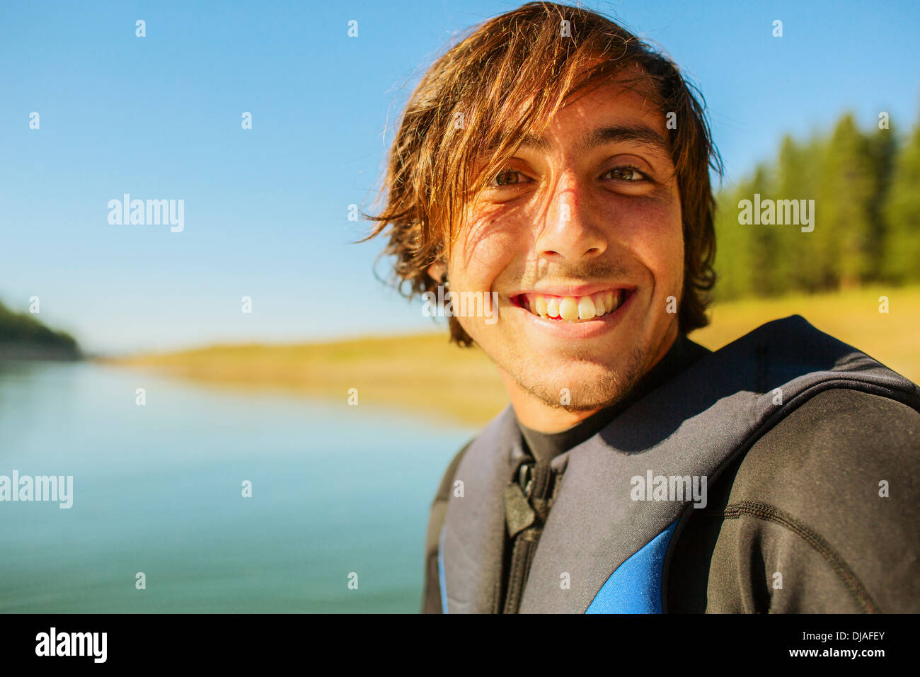 Caucasian man smiling by rural lake Stock Photo
