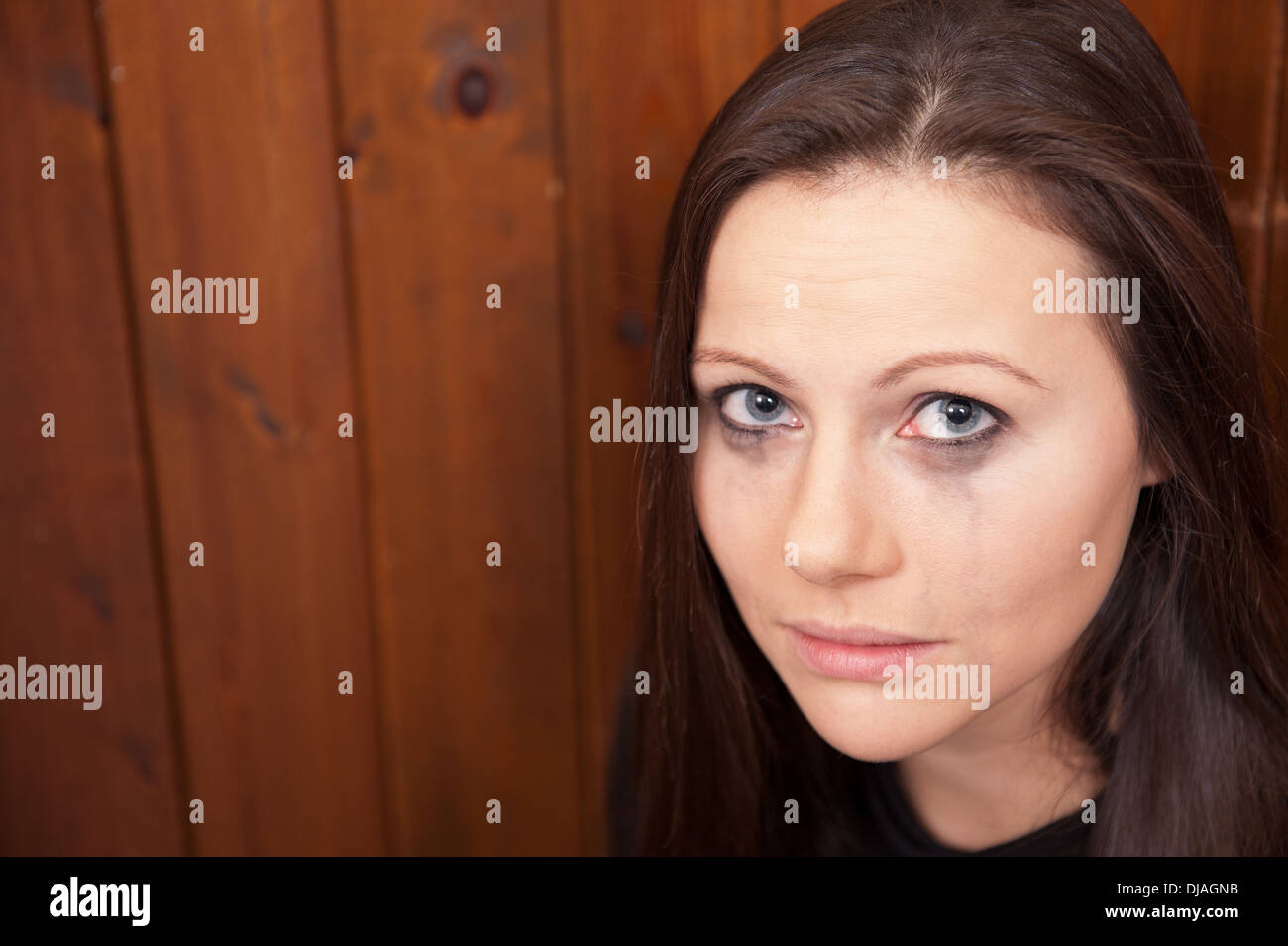 Upset looking young woman with her eye make-up running down her face. Maybe a victim of domestic violence, bullying or abuse. Stock Photo