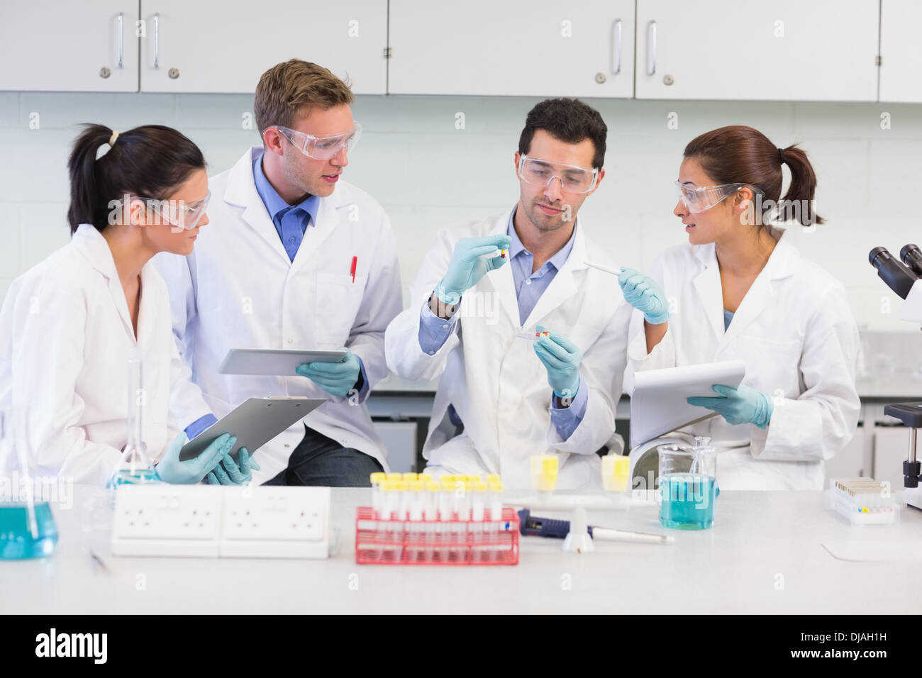 Scientists with tablet PC working on experiment at lab Stock Photo