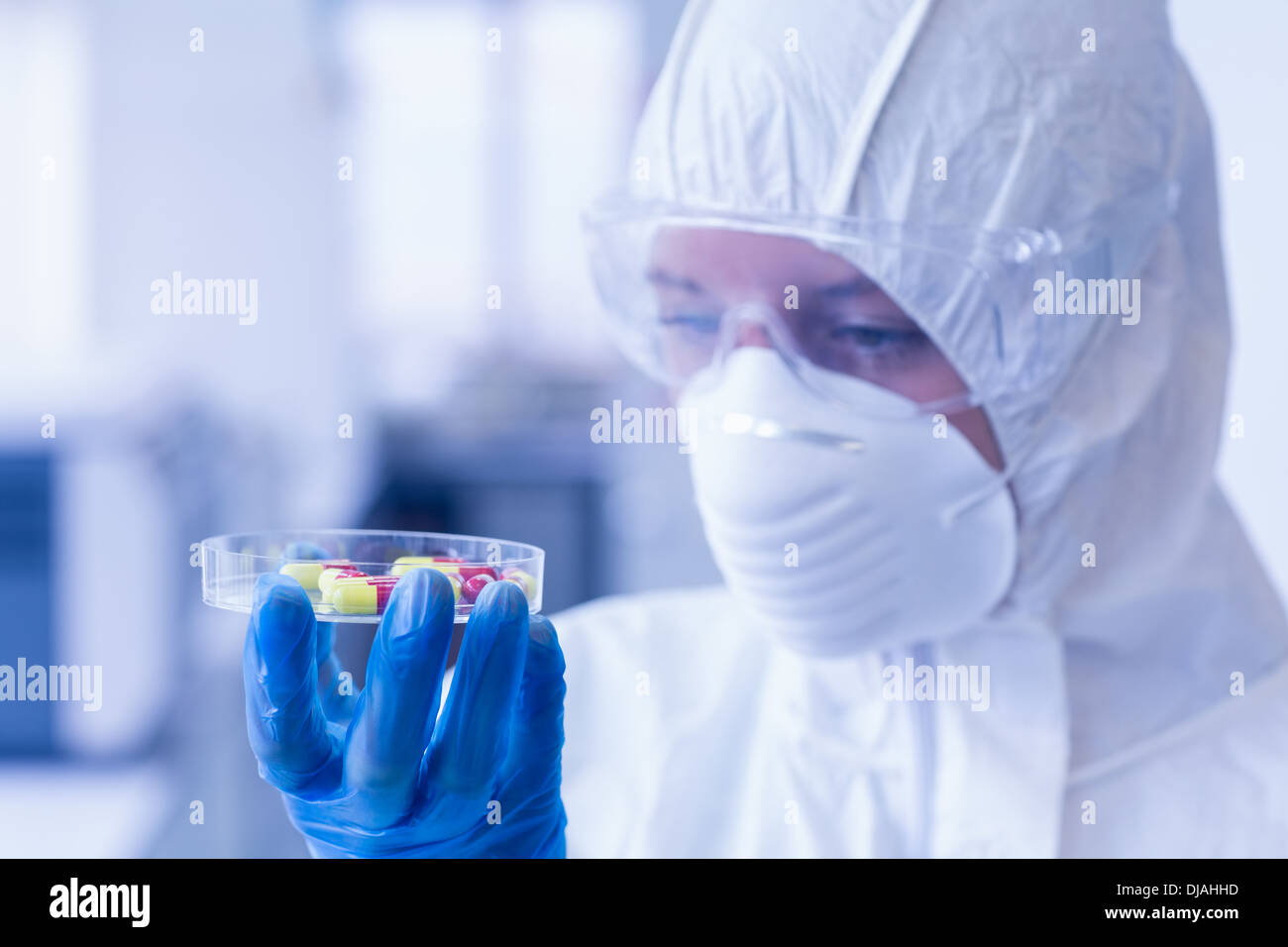 Scientist in protective suit analyzing pills Stock Photo
