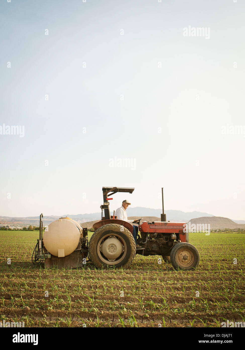Caucasian farmer driving tractor in crop field Stock Photo